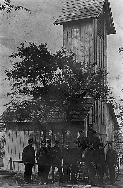 Die Mannschaft der FF Tanzelsdorf vor ihrem ersten hölzernen Rüsthaus mit Schlauchturm